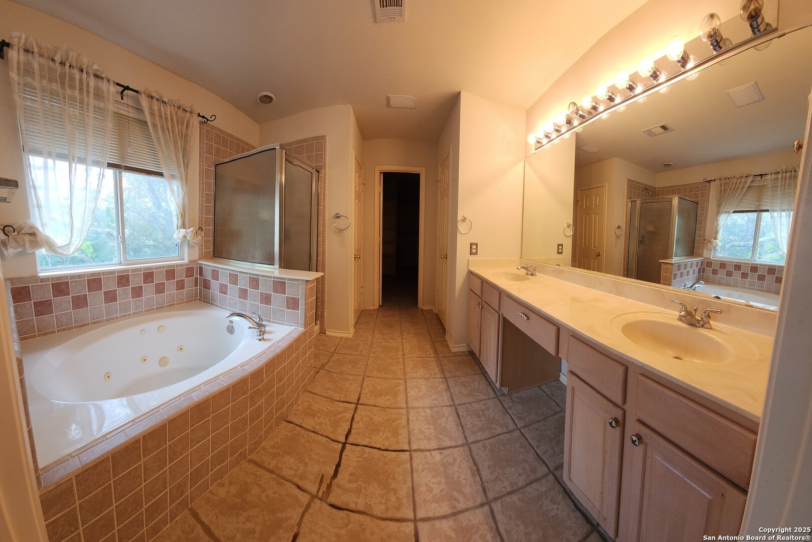 9318 Grand Cedar Helotes, TX 78023 - Photo 25 of 32 a spacious bathroom with a bathtub sink and mirror