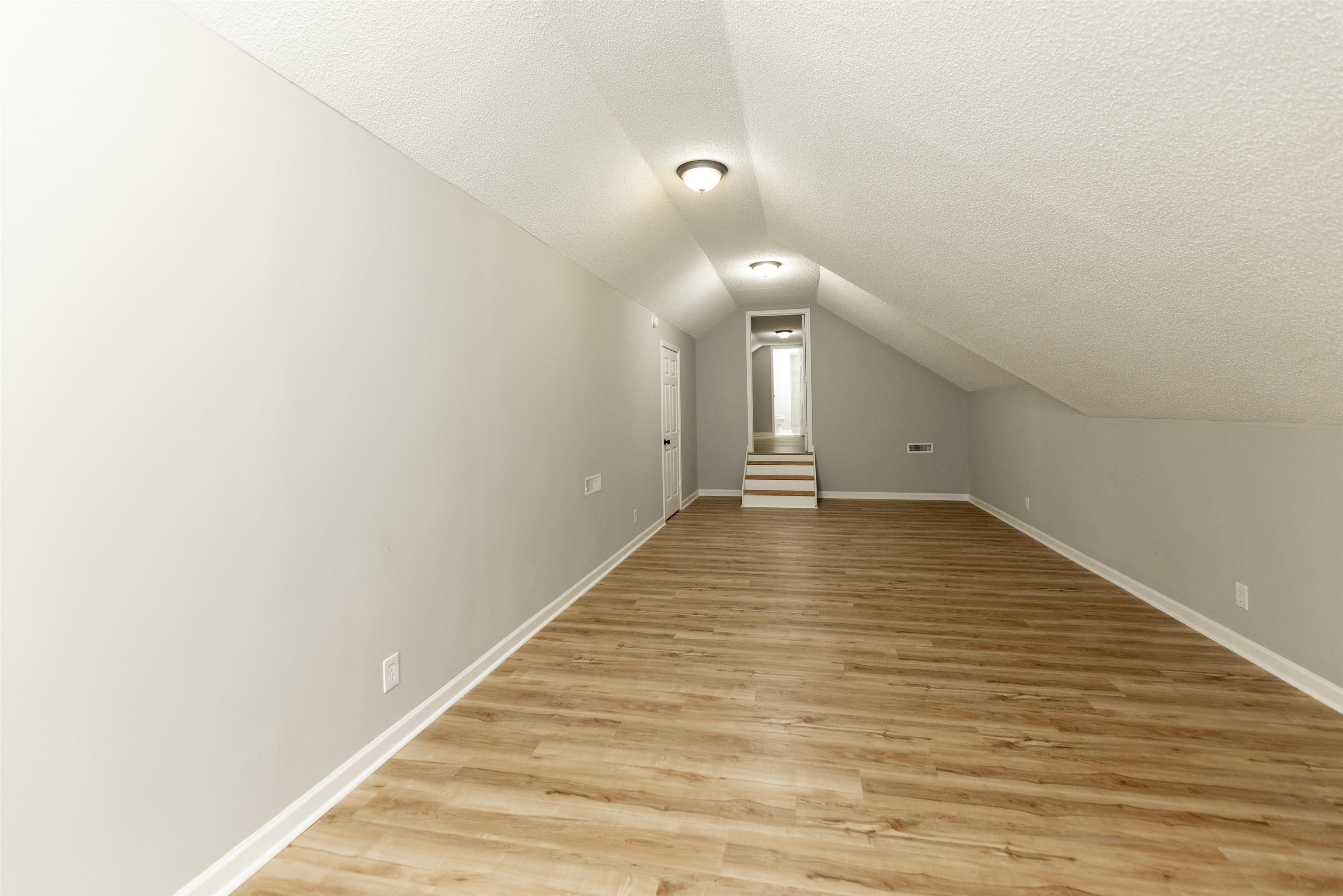 7421 Richmond Road Memphis, TN 38125 - Photo 32 of 39 Spacious room featuring wood-finish flooring, light grey walls, white trim, and sloped ceilings