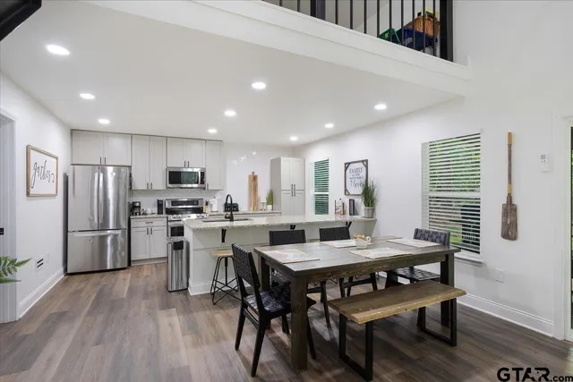 a kitchen with stainless steel appliances a dining table chairs stove refrigerator and microwave