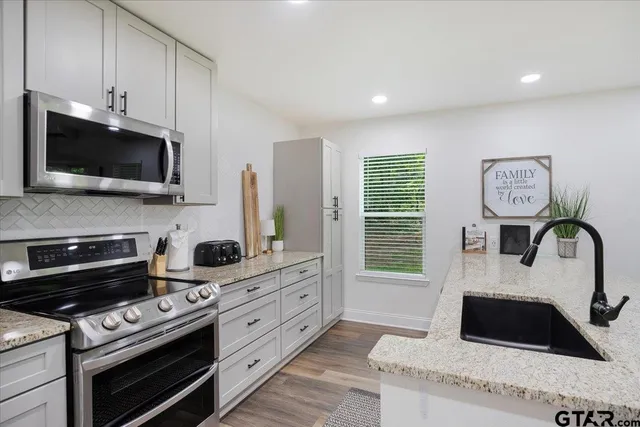 a kitchen with granite countertop cabinets stainless steel appliances and a window