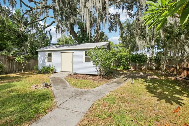 a view of a house with large trees and wooden fence