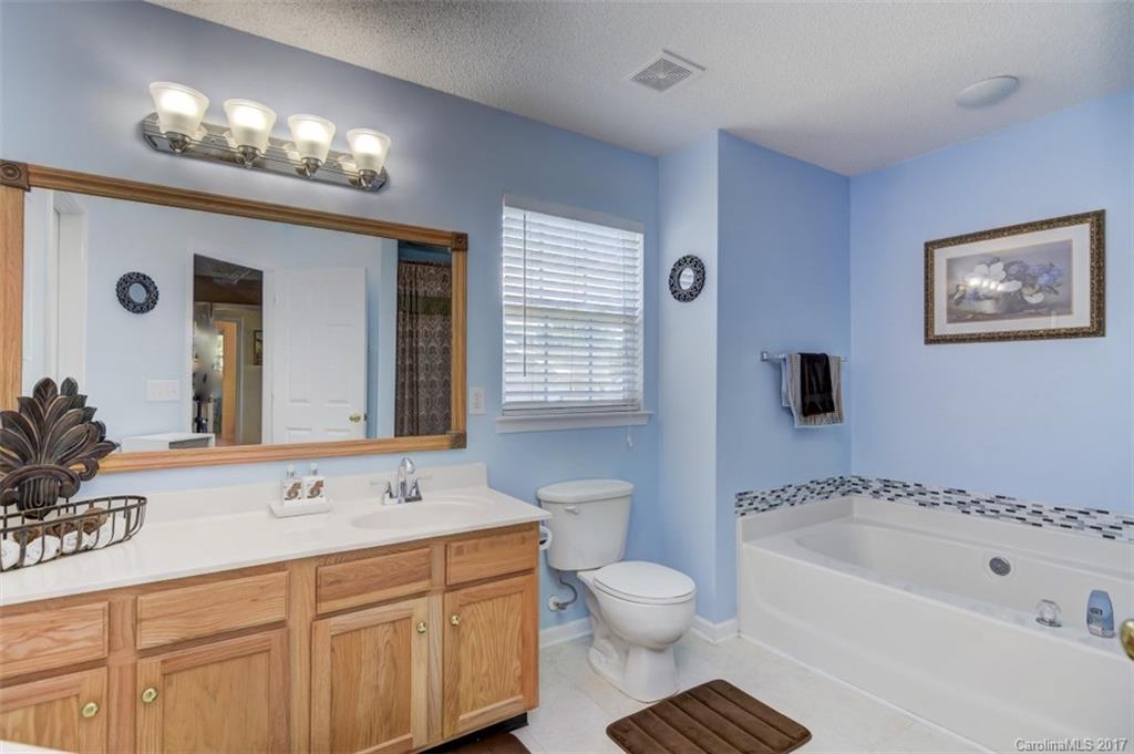 7467 Fallen Timber Lane, Unit 27 Tega Cay, SC 29708 - Photo 19 of 24 a spacious bathroom with a bathtub a sink and a large mirror