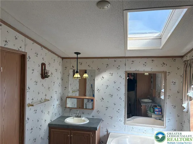 a bathroom with a granite countertop sink a mirror and shower