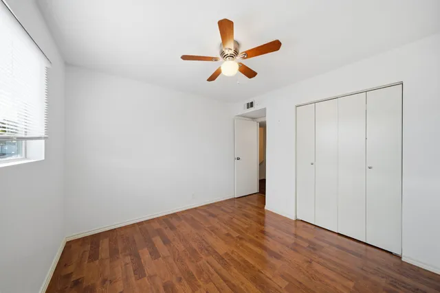 a view of empty room with wooden floor and fan