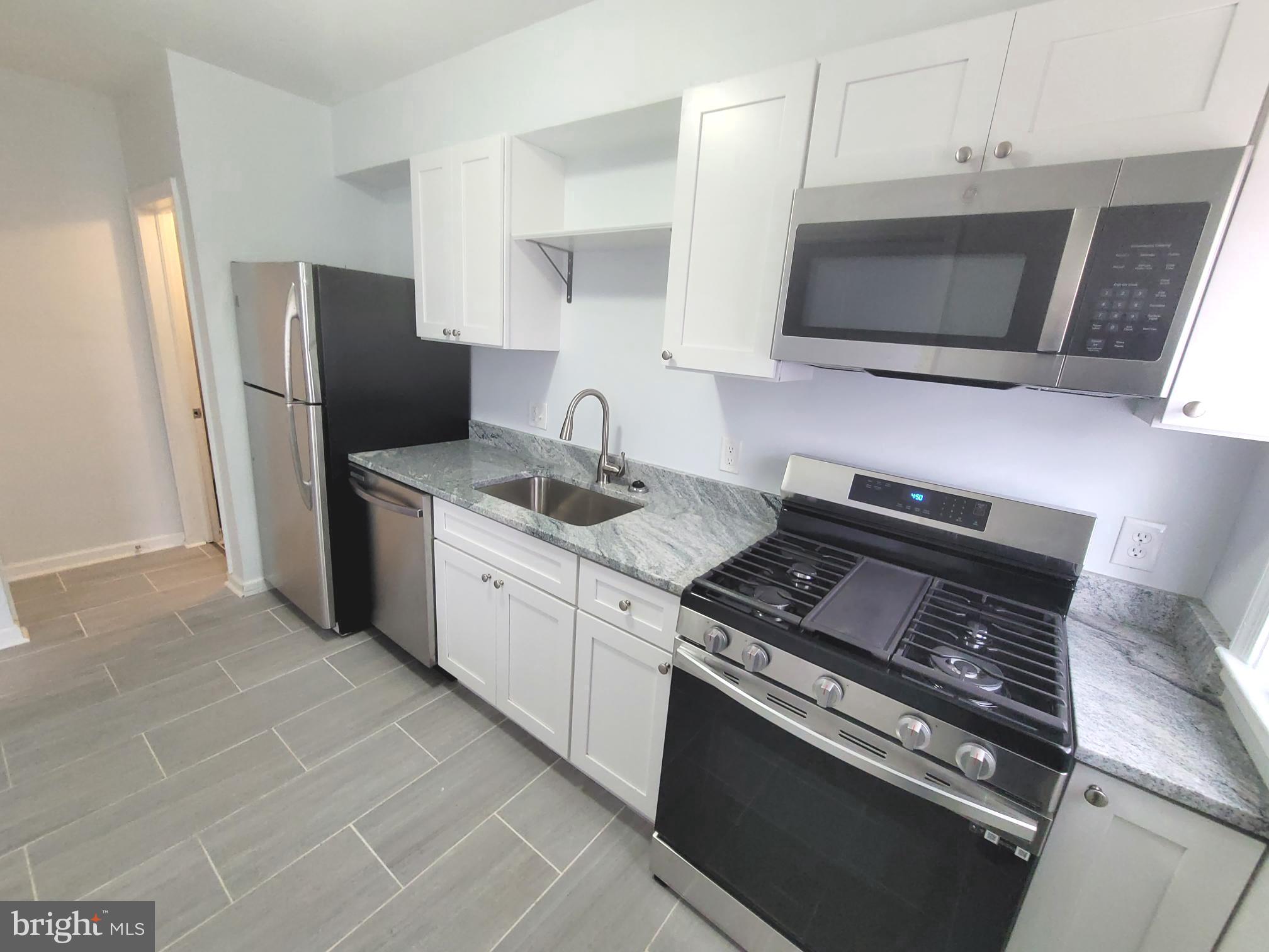 4603 Marble Hall Road Baltimore, MD 21239 - Photo 6 of 24 a kitchen with stainless steel appliances a stove a microwave a sink and cabinets