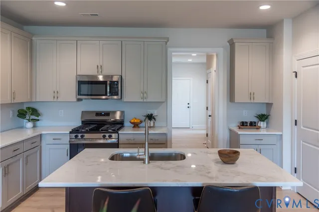 a kitchen with stainless steel appliances a sink a stove a refrigerator and cabinets