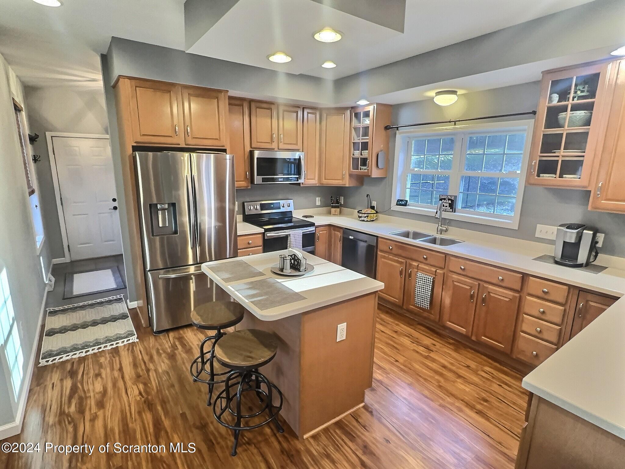 514 Brace Road Dallas, PA 18612 - Photo 3 of 49 a kitchen with stainless steel appliances granite countertop a refrigerator a sink dishwasher a stove and white countertops with wooden floor