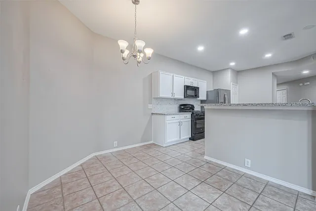 a kitchen with stainless steel appliances granite countertop a sink a stove a refrigerator and white cabinets