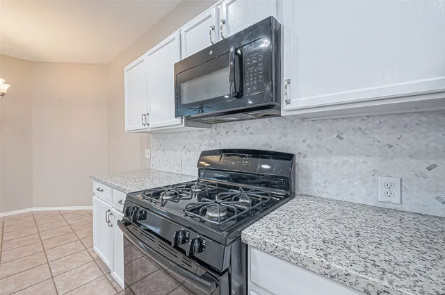 a kitchen with stainless steel appliances granite countertop white cabinets and a stove top oven