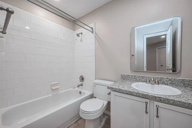 a bathroom with a granite countertop sink a toilet and bathtub