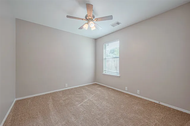 an empty room with a window and a fan
