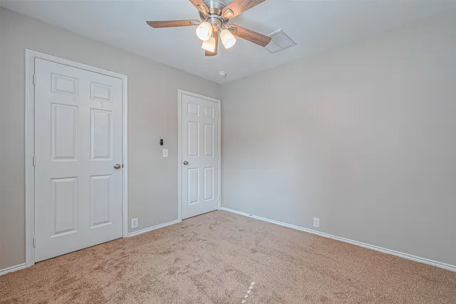 an empty room with closet and a chandelier fan