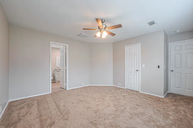 a view of an empty room and chandelier fan