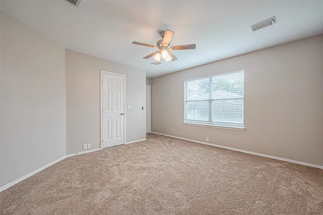 an empty room with windows and fan