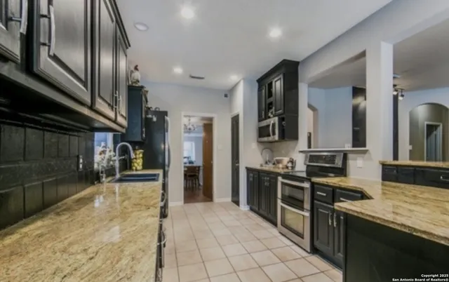 a kitchen with stainless steel appliances granite countertop a stove a sink and a refrigerator