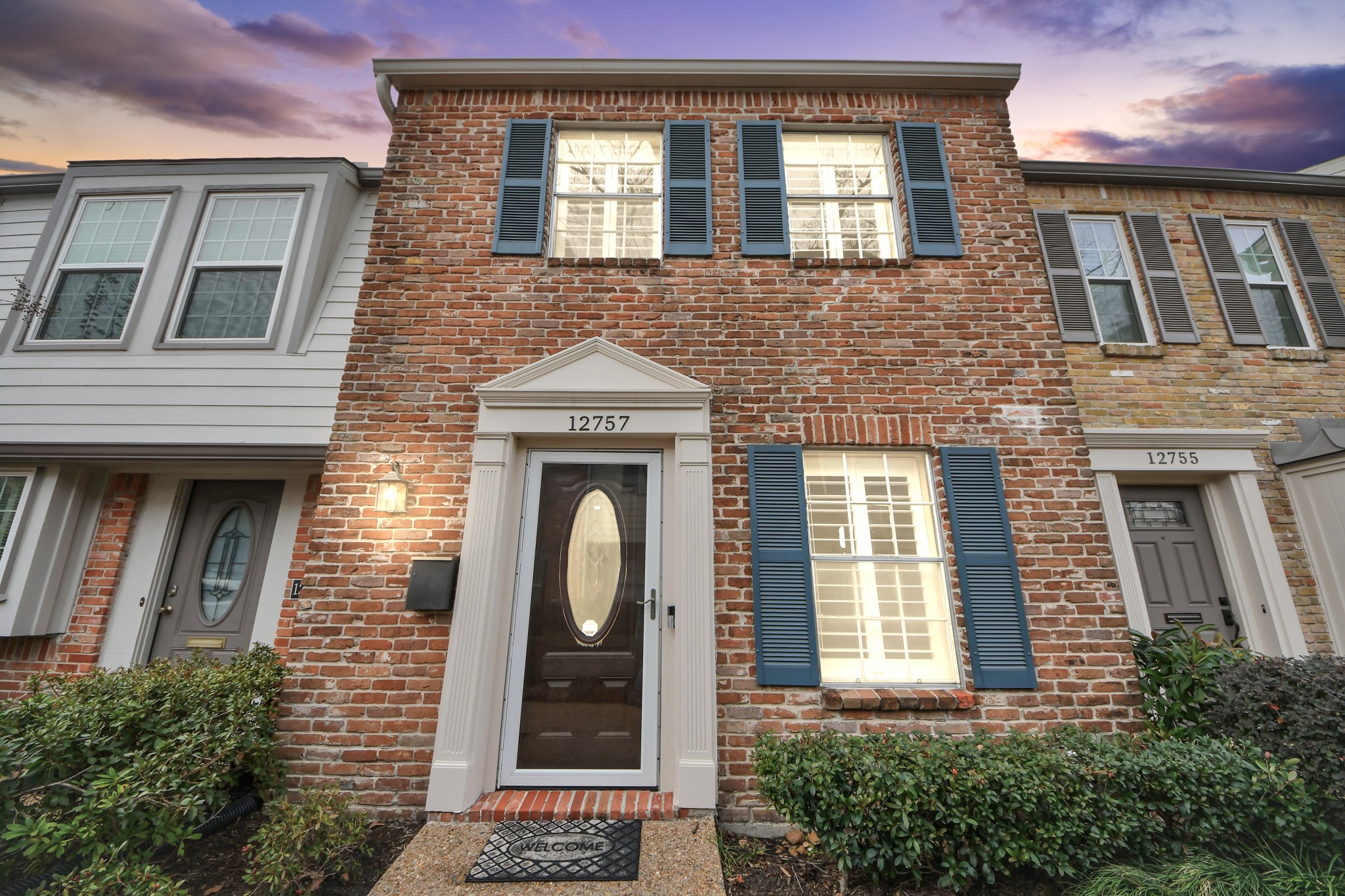Attractive condo facade showcasing warm-toned brick, a fiberglass entry door, and traditional windows with grid detailing.