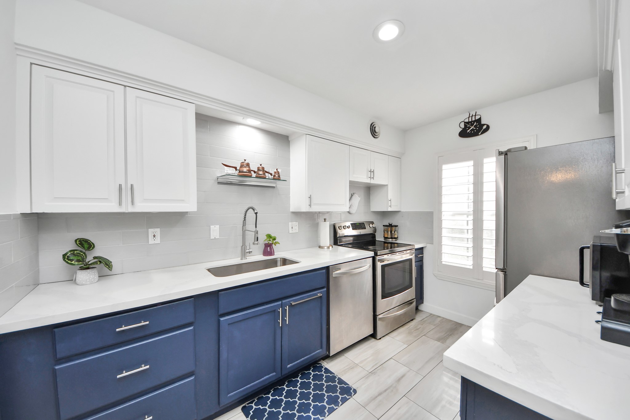 12757 Huntingwick Drive, Unit 142 Houston, TX 77024 - Photo 16 of 36 Stylish kitchen showcasing white upper cabinets, contrasting lower cabinetry, and updated appliances.