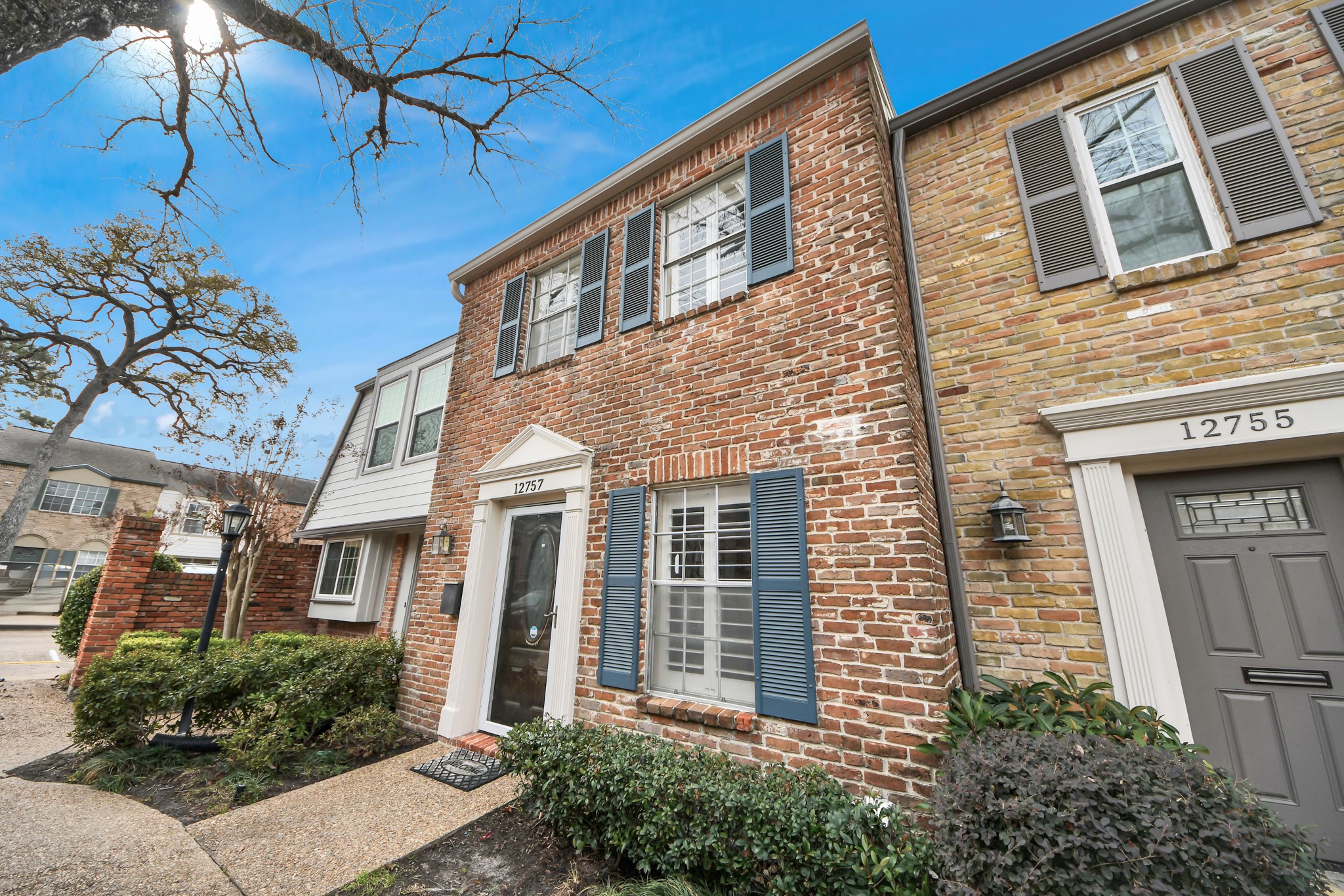 12757 Huntingwick Drive, Unit 142 Houston, TX 77024 - Photo 2 of 36 Classic brick exterior with decorative shutters and windows featuring grids, offering a timeless and well-maintained appearance.