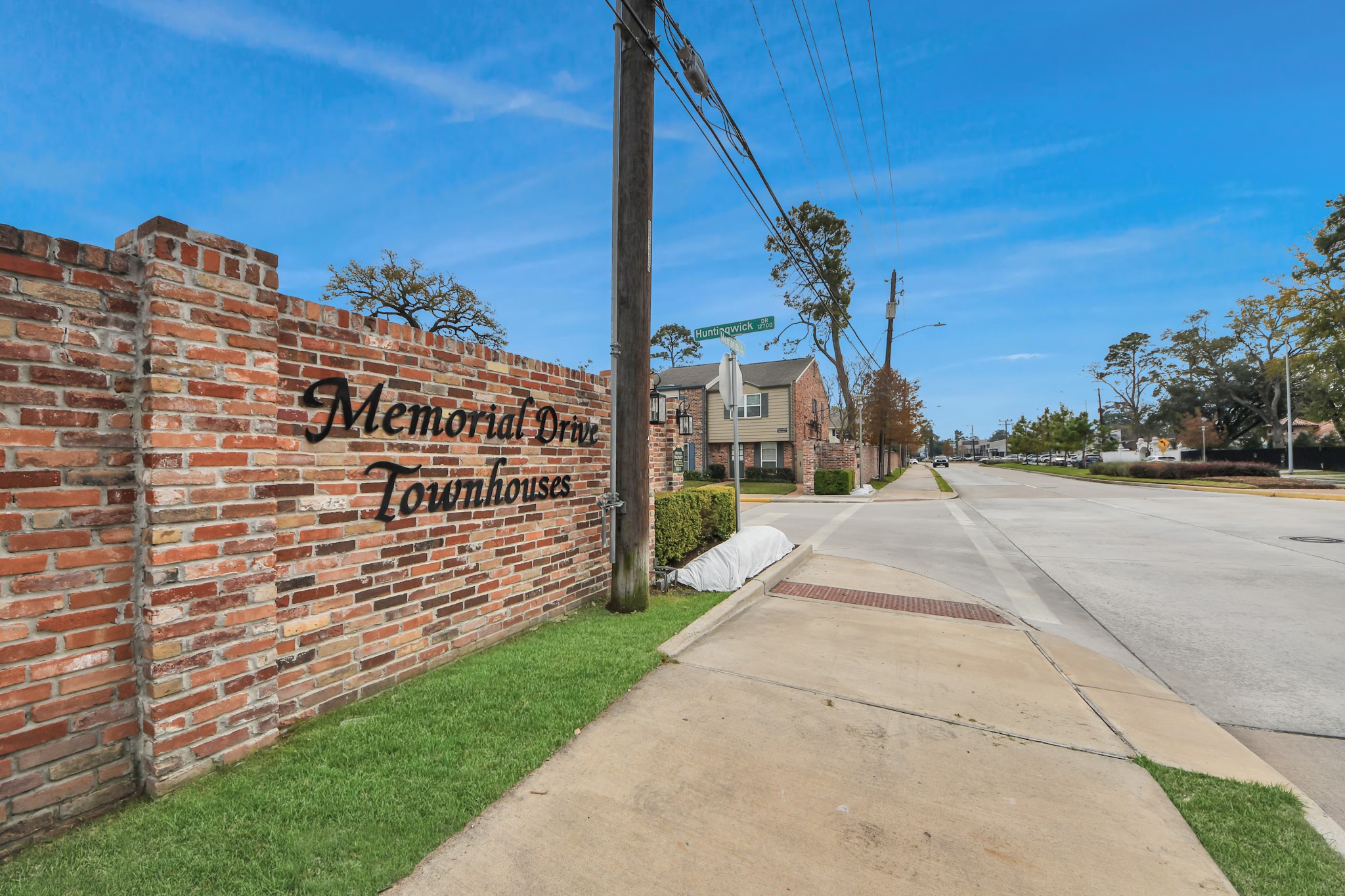 12757 Huntingwick Drive, Unit 142 Houston, TX 77024 - Photo 36 of 36 Well-maintained street featuring a brick perimeter wall, clean surroundings, and an inviting community feel.