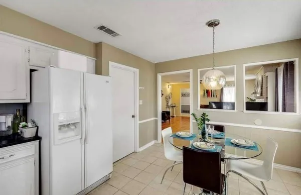 a dining room with stainless steel appliances kitchen island granite countertop a refrigerator a sink a dining table and chairs with wooden floor