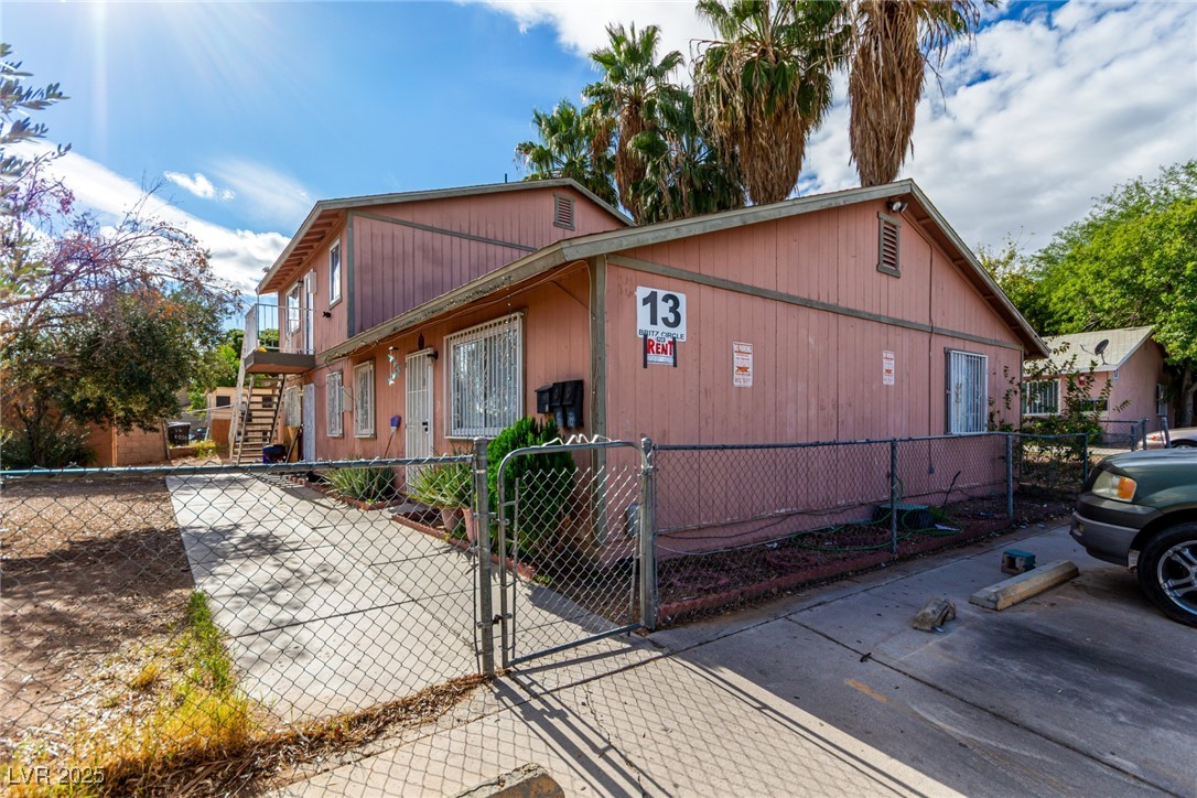 View of side of property featuring a gate, a fenced front yard, and stairs