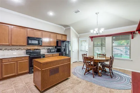 a kitchen with stainless steel appliances granite countertop a stove top oven a sink a dining table and chairs with wooden floor