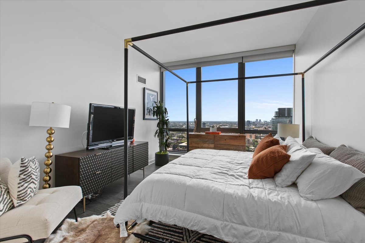 Undisclosed Address Chicago, IL 60607 - Photo 7 of 18 a bedroom with a bed and a flat tv screen on dresser