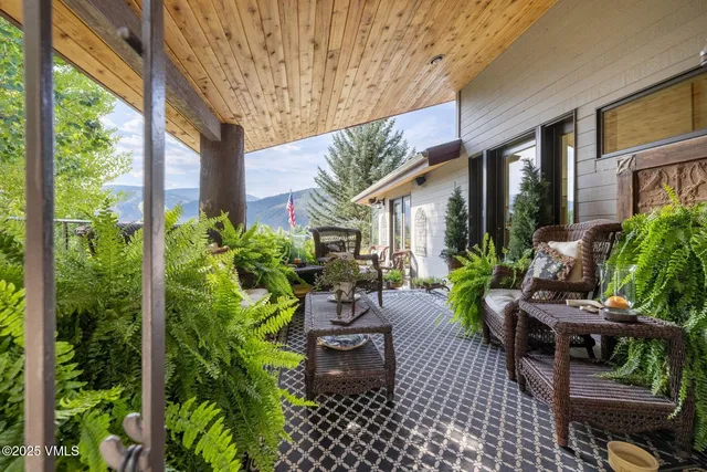 a view of a patio with table and chairs potted plants and floor to ceiling window