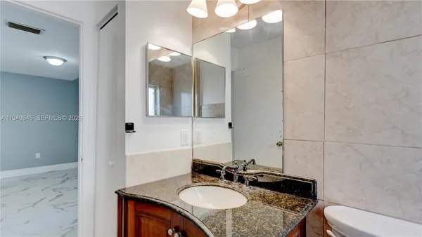 a bathroom with a granite countertop sink and a mirror