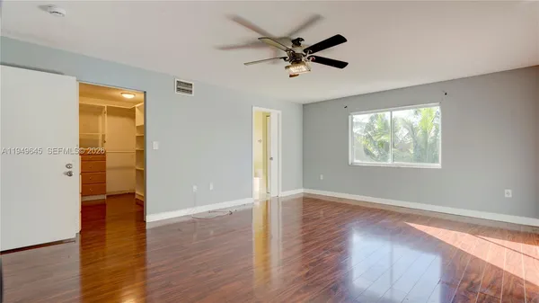 a view of empty room with wooden floor and ceiling fan