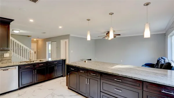 a kitchen with granite countertop a sink a counter space appliances and cabinets