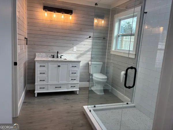 a bathroom with a granite countertop toilet a sink a mirror and shower