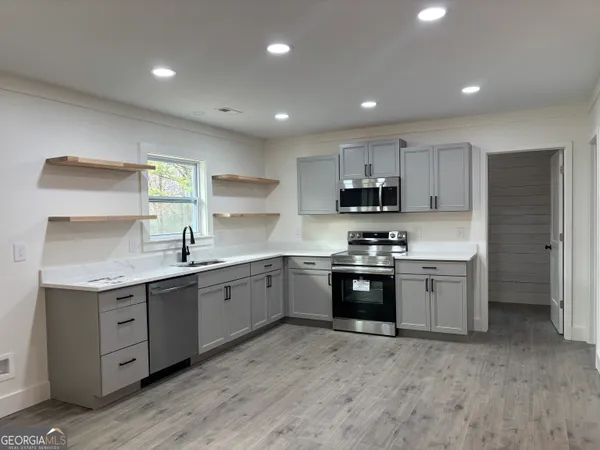 a large kitchen with stainless steel appliances granite countertop a sink and cabinets
