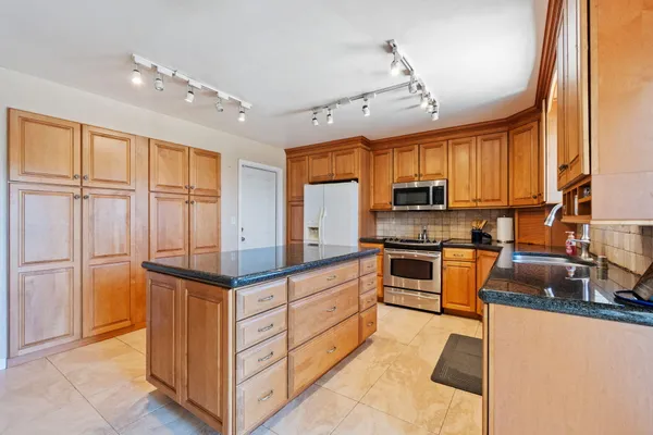 a kitchen with stainless steel appliances granite countertop a stove top oven a refrigerator a sink and dishwasher with wooden floor