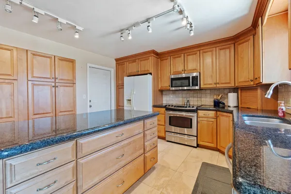 a kitchen with granite countertop a sink stainless steel appliances and cabinets