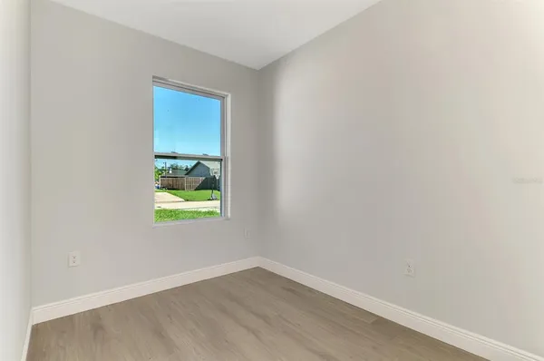 an empty room with wooden floor and a ceiling fan