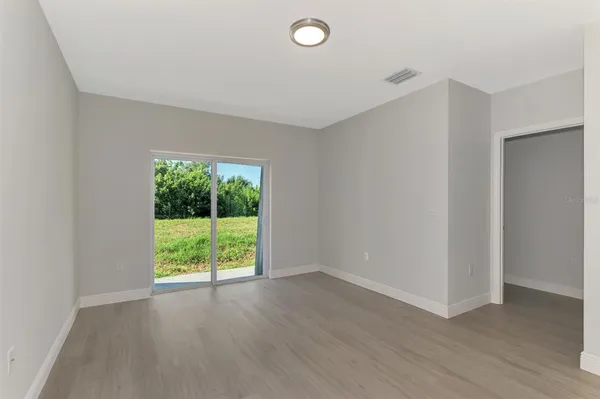 a view of an empty room with wooden floor and closet