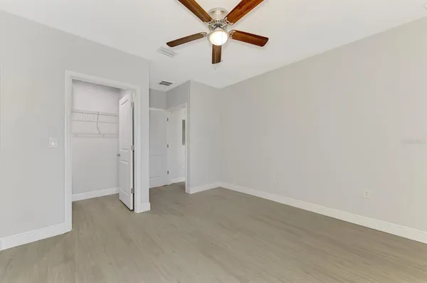 a view of an empty room with closet and a mirror