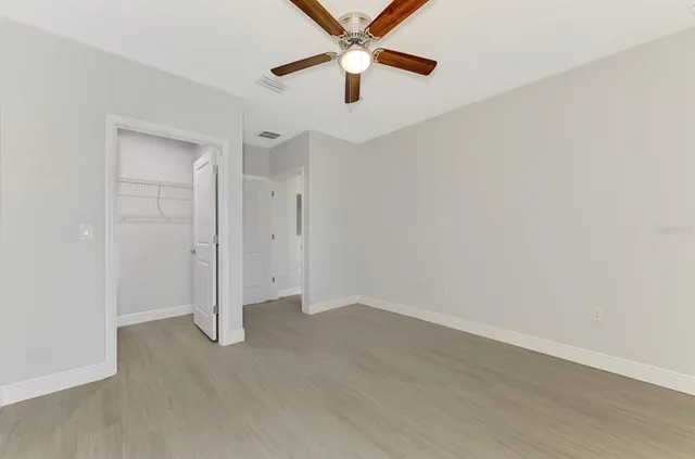 a view of an empty room with closet and a mirror