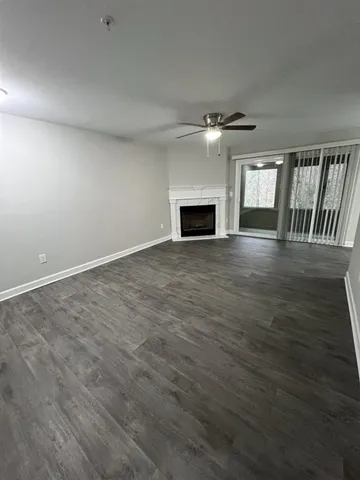 an empty room with wooden floor fireplace and windows