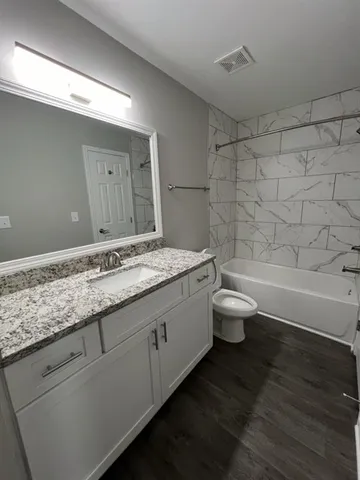 a bathroom with a granite countertop toilet a sink and a bathtub