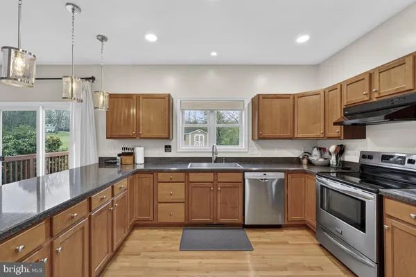 a kitchen with stainless steel appliances granite countertop a refrigerator a sink a stove and wooden floors