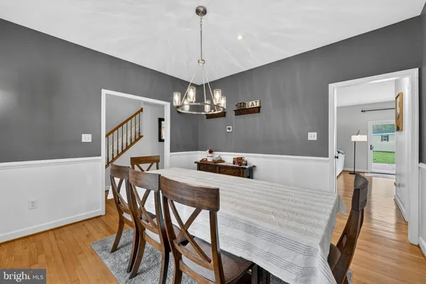 a dining room with wooden floor a chandelier a wooden table and chairs