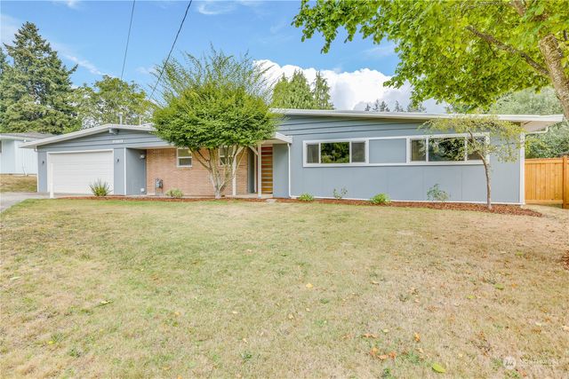 a front view of house with yard and trees in the background