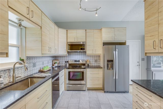 a kitchen with granite countertop a sink stainless steel appliances and cabinets