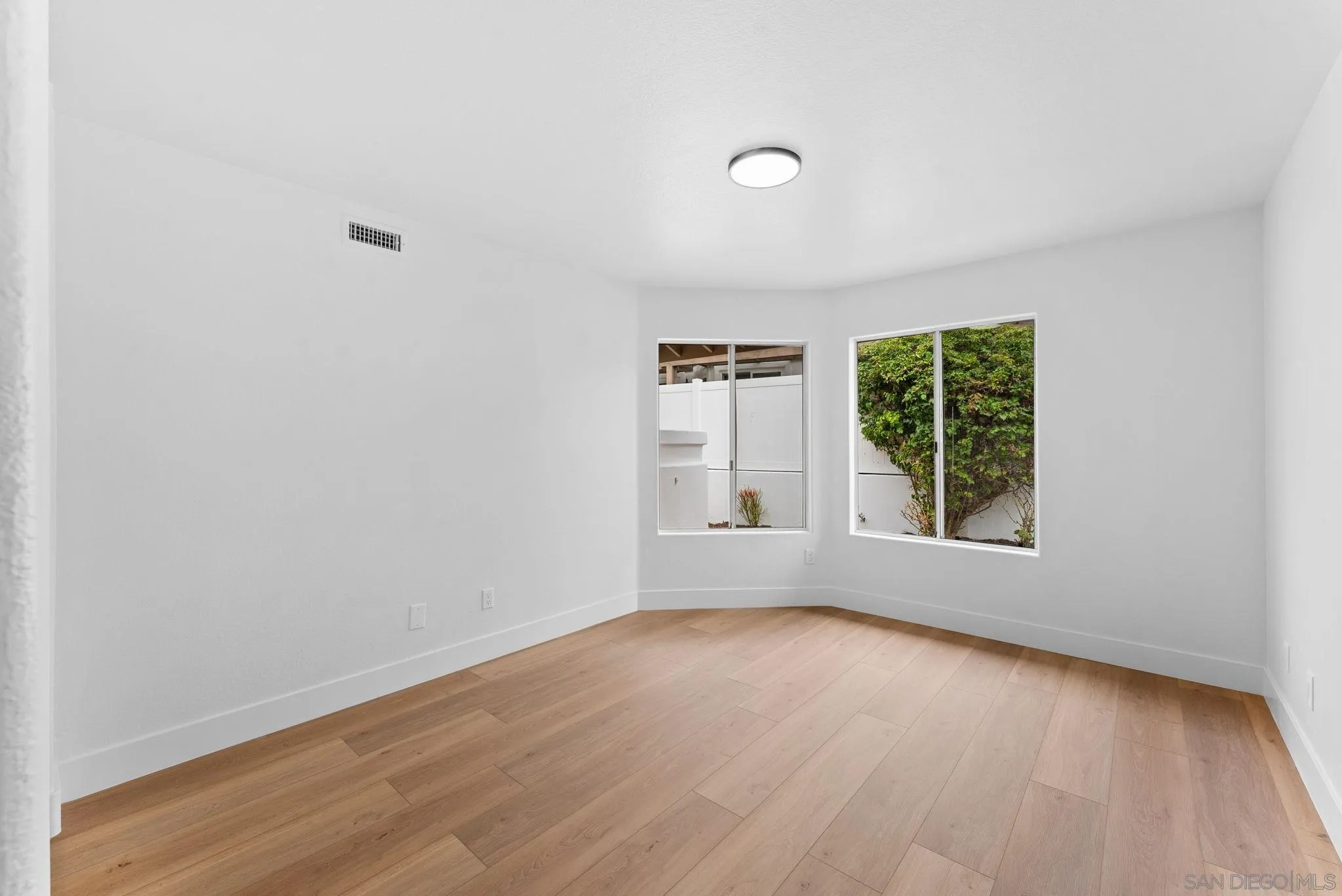 4695 Adra Way Oceanside, CA 92056 - Photo 24 of 29 an empty room with wooden floor and windows