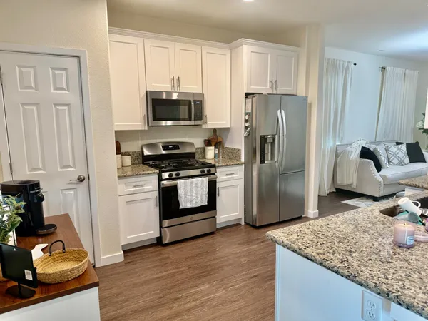 a kitchen with stainless steel appliances granite countertop a refrigerator stove and white cabinets