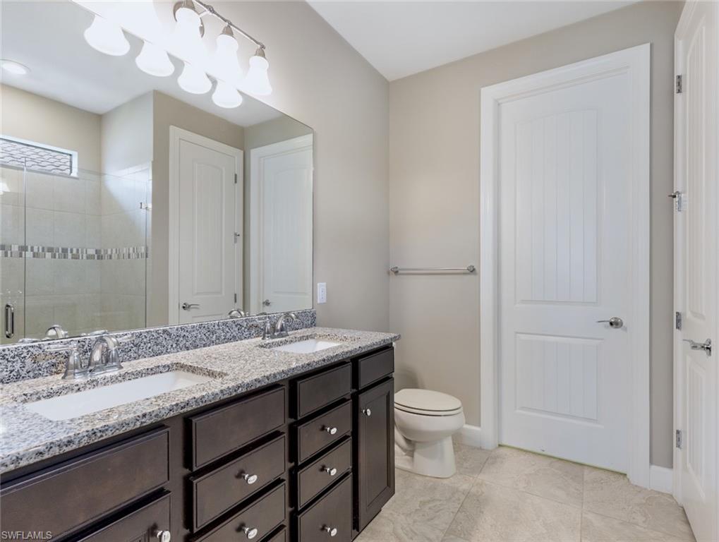 19953 Beverly Park Road Estero, FL 33928 - Photo 14 of 35 a bathroom with a granite countertop sink a toilet and a mirror