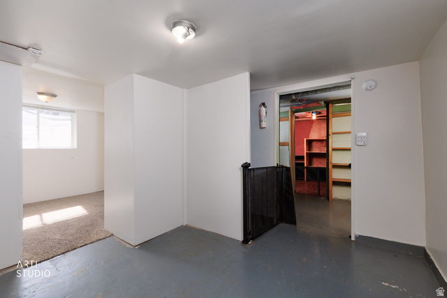 146 West 200 N Street Springville, UT 84663 - Photo 18 of 29 Lower level space featuring painted concrete flooring, carpeted area with natural light from a window, and an open doorway to a storage area with built-in shelving