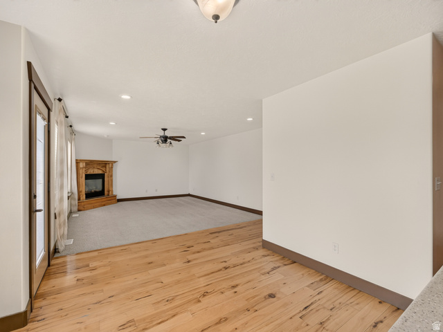 1279 West 1500th Street North Mapleton, UT 84664 - Photo 27 of 83 Interior space featuring wood-finish flooring transitioning to carpet, a corner fireplace with a wood mantle, a ceiling fan, recessed lighting, and a glass-paned door